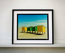 Load image into Gallery viewer, &#39;Beach Lockers&#39; was captured on a glorious spring day in Wildwood, New Jersey. It features bold yellow and green shapes against a beach and bright blue sky. Taken in 2013, this photograph was first executed in Richard&#39;s darkroom in April 2020. Colour is key in Richard&#39;s work, and through the simplicity of this artwork, it really shows. Whilst photographing on the East Coast of America, Richard drew parallels of familiarity to the East Coast of England.