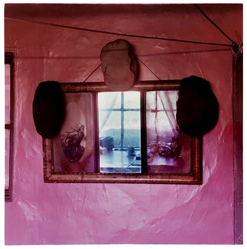 Photograph by Richard Heeps. The fenland landscape reflects beyond the room in the mirror on the pink cottage wall adorned by three flat caps