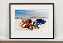 Load image into Gallery viewer, &#39;Christine&#39;s &#39;52 Henry J &amp; teardrop&#39; was captured in Bonneville Salt Flats, Utah, the iconic home of speed. This photograph shows the mountains in the distance meeting and contrasting with the flatness of the salt pan, whilst a pair of retro spectators look out at the speeding cars in the distance.