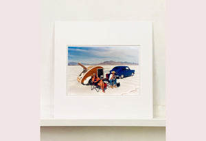 'Christine's '52 Henry J & teardrop' was captured in Bonneville Salt Flats, Utah, the iconic home of speed. This photograph shows the mountains in the distance meeting and contrasting with the flatness of the salt pan, whilst a pair of retro spectators look out at the speeding cars in the distance.