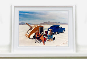 'Christine's '52 Henry J & teardrop' was captured in Bonneville Salt Flats, Utah, the iconic home of speed. This photograph shows the mountains in the distance meeting and contrasting with the flatness of the salt pan, whilst a pair of retro spectators look out at the speeding cars in the distance.