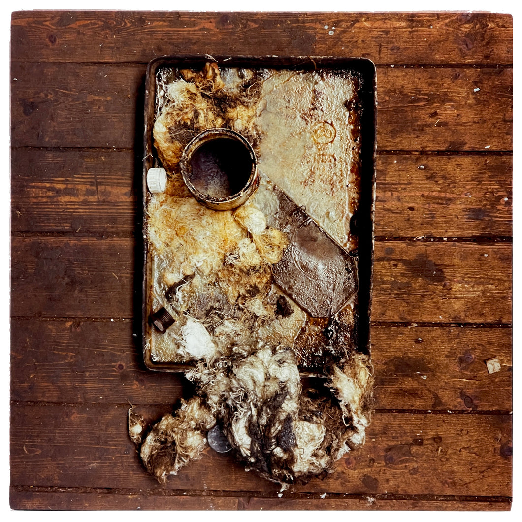 Photograph by Richard Heeps. A broken drip tray sits in the middle of a wooden slated table. 