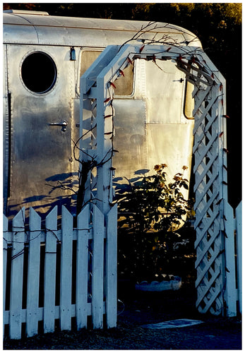 Part of Richard Heeps' 'Dream in Colour' series, this photograph features a white picket fence entrance to the Royal Mansion at the Shady Dell Trailer Park in Bisbee. Arizona. 