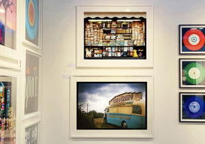 A moody Fenland sky is backdrop to a classic British Fish & Chips Van. The typography and the van itself has a fun fairground feel, contrary to the muted tones of this piece. Part of Richard Heeps series, 'A View of the Fens from the Car with Wings'.