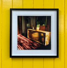 Load image into Gallery viewer, Light streams into the mid-century interior of the Harmony Motel, casting a patterned shadow across the rattan furniture and cactus. This cinematic motel room interior photograph taken in Twentynine Palms, California, is part of Richard Heeps&#39; &#39;Dream in Colour&#39; series.