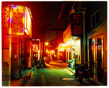 Load image into Gallery viewer, Photograph by Richard Heeps.  A narrow road in Hutong, brightly lit orange signs light the way down the road.