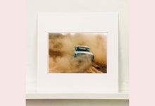 Load image into Gallery viewer, &#39;Mercury in the Dust I&#39; shows a classic American car donut driving on a Norfolk beach in the East of England. This photograph was captured at Hemsby Rock and Roll weekend, and is part of Richard Heeps&#39; Man&#39;s Ruin&#39; series.