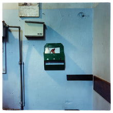 Load image into Gallery viewer, Photograph by Richard Heeps. A light blue factory wall with a green milk rack at its centre, with a glass pint of milk and a photo of a woman attached to the back of the milk rack.