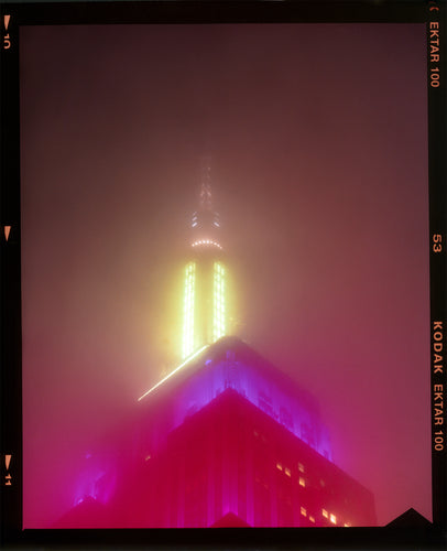 NOMAD VII (Film Rebate), New York, photography by Richard Heeps capturing the iconic Empire State building in the mist. Part of a sequence of photographs capturing the art deco architecture illuminated in changing colours. This 6x7 format edition is bordered by the Kodak film rebate. This artwork is part of Richard's portfolio of street photography he is building up which depict the colour, fabric and structure of cities with distinct style