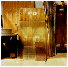 Load image into Gallery viewer, Photograph by Richard Heeps.  Inside the workshop old doors, bits of wood and corrugated plastic are leaning against the wall.  An old door has No.25 printed on it.