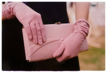 Load image into Gallery viewer, Photograph by Richard Heeps.  Pink clutch bag being held by matching pink gloved hands, set against the wearer&#39;s black dress.