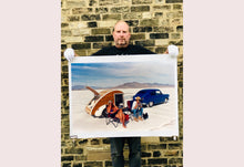 Load image into Gallery viewer, &#39;Christine&#39;s &#39;52 Henry J &amp; teardrop&#39; was captured in Bonneville Salt Flats, Utah, the iconic home of speed. This photograph shows the mountains in the distance meeting and contrasting with the flatness of the salt pan, whilst a pair of retro spectators look out at the speeding cars in the distance.