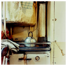 Load image into Gallery viewer, Photograph by Richard Heeps.  A well worn aga provides a home for a big steel kettle.  Above, is an old boiler.