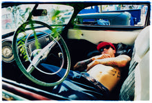 Load image into Gallery viewer, Photograph by Richard Heeps. Inside a classic American car and lying on the seats is a man resting.