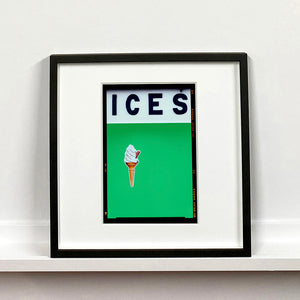 Black framed photograph by Richard Heeps.  At the top black letters spell out ICES and below is depicted a 99 icecream cone sitting left of centre against a green coloured background.  
