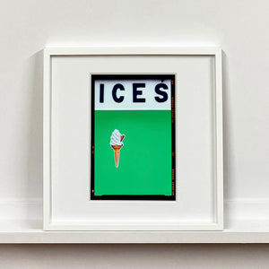 White framed photograph by Richard Heeps.  At the top black letters spell out ICES and below is depicted a 99 icecream cone sitting left of centre against a green coloured background.  