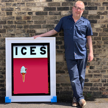 Load image into Gallery viewer, Photograph by Richard Heeps.  Richard Heeps holds a white framed print. At the top of the print, black letters spell out ICES and below is depicted a 99 icecream cone sitting left of centre against a raspberry coloured background.  