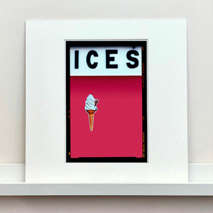 Mounted photograph by Richard Heeps.  At the top black letters spell out ICES and below is depicted a 99 icecream cone sitting left of centre against a raspberry coloured background.  