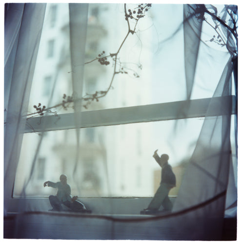 Interior photograph by Richard Heeps taken in Hong Kong featuring figurines in Tai Chi form sitting on a window sill and veiled by a fine net curtain.
