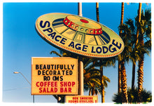 Load image into Gallery viewer, Photograph by Richard Heeps.  This retro sign takes the shape and design of a vintage UFO sign with Space Age Lodge written around the ledge of the UFO.  This is set against Arizona&#39;s palm trees and blue skies.