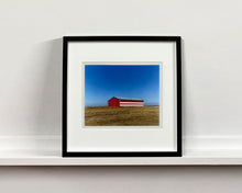 Load image into Gallery viewer, &#39;Stars &amp; Stripes Barn&#39; shows a depiction of the American flag painted on this isolated building in Oakhurst, California. It sits on the horizon against a vast bright blue sky. This artwork is part of Richard Heeps&#39; &#39;Dream in Colour&#39; series.
