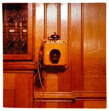 Load image into Gallery viewer, Photograph by Richard Heeps.  Wooden pannelling with an antique wall mount crank wall telephone in the same rich mahogony wood as the wall.