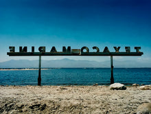 Load image into Gallery viewer, Texaco Marine sign on the Salton Sea beach, with a blue sky and mountains in the distance