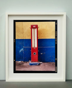 A red retro tyre pump against a yellow and blue painted wall, in the Porta Genova area of Milan. 