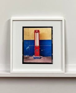 A red retro tyre pump against a yellow and blue painted wall, in the Porta Genova area of Milan. 
