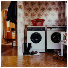 Load image into Gallery viewer, Photograph by Richard Heeps.  A 1980s family utility room with a washing machine, a tumble dryer, brown linoleum and flowery wallpaper.