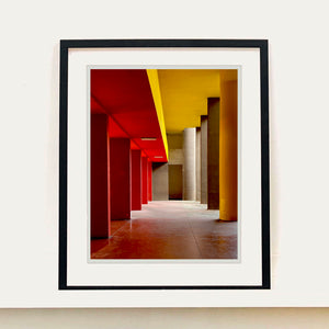 Monte Amiata housing, Gallaratese Quarter, Milan. Red and yellow brutalist architecture street photography by Richard Heeps framed in black.