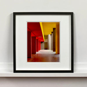 Monte Amiata housing, Gallaratese Quarter, Milan. Red and yellow brutalist architecture street photography by Richard Heeps Framed in black.