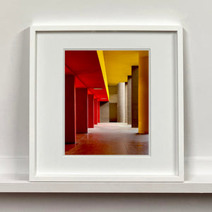 Monte Amiata housing, Gallaratese Quarter, Milan. Red and yellow brutalist architecture street photography by Richard Heeps framed in white.