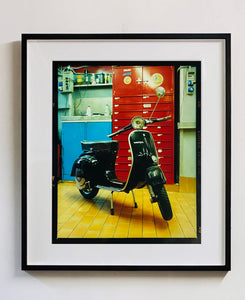 A black vespa against a red, blue and yellow interior. Photographed in Milan, Italy. 