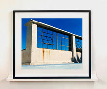 Load image into Gallery viewer, &#39;Window of the World, Zzyzx Resort Pool&#39;, photographed in Soda Dry Lake, California shows window pains and a distressed wall, against a bright blue background of sky. This artwork is part of Richard&#39;s &#39;Dream in Colour&#39; series. 