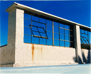 'Window of the World, Zzyzx Resort Pool', photographed in Soda Dry Lake, California shows window pains and a distressed wall, against a bright blue background of sky. This artwork is part of Richard's 'Dream in Colour' series. 