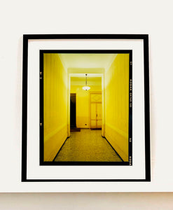 A yellow glow fills the corridor of an apartment foyer in Milan.