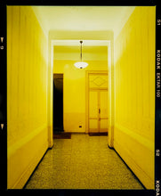 Load image into Gallery viewer, A yellow glow fills the corridor of an apartment foyer in Milan.
